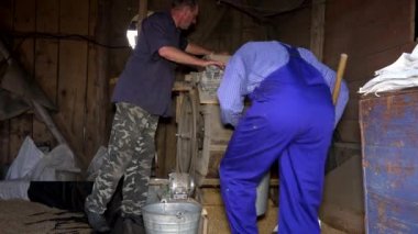 İki adam ile kırsal çiftlik ahırda vintage makine tahıl Eleme