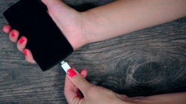 el ahşap arka plan üzerinde siyah akıllı telefon aygıtı için beyaz kablosunu bağlayın