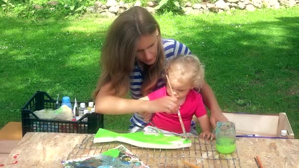 Mother with her toddler daughter girl paint wooden fish decoration — Stockvideo
