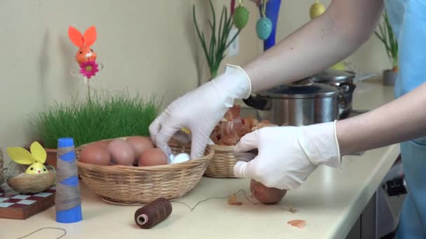 Vrouwelijke handen met handschoenen zetten UI shell en witte ei in Sok — Stockvideo