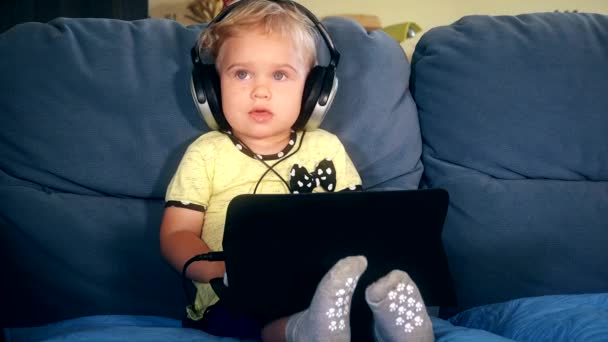 Malé roztomilé dítě s velkými sluchátky sledoval karikatury v tabletovém počítači — Stock video
