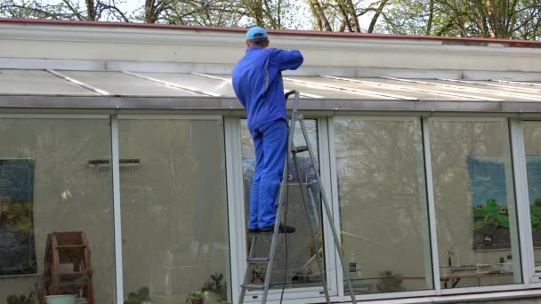 Techo de la casa de cristal de limpieza hombre con herramienta de alta presión en la naturaleza . — Vídeos de Stock