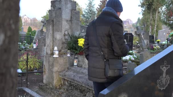 Homme mis bougie sur la tombe après femme mère perte dans le cimetière. 4K — Video