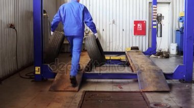 erkek makinist aşınmış lastikleri taşırlar. Saklamak lastikleri kış sezonu için kullanılan.