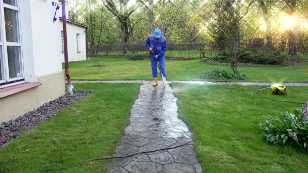 Housekeeper cara lavar caminho concreto perto de sua casa . — Vídeo de Stock