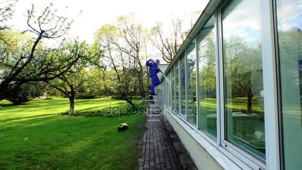 Guy schoonmaken van de buitenkant van het gebouw met hoge druk waterstraal. — Stockvideo