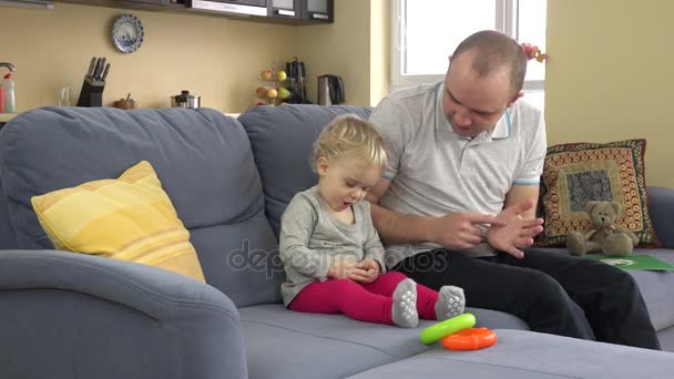 Pai brincalhão se divertir com bebê menina no sofá em casa. homem cócegas criança menina — Vídeo de Stock