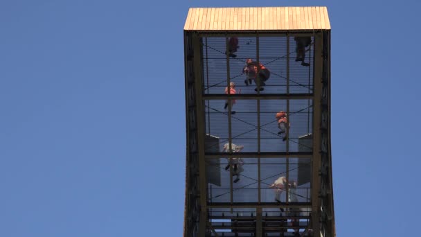 Храбрые люди туристы ходят по прозрачному полу высоко в небе на смотровой башне. 4K — стоковое видео