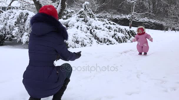 Glückliche kleine Mädchen zu Fuß in Richtung Mutter auf Schnee in der Wintersaison. 4k — Stockvideo