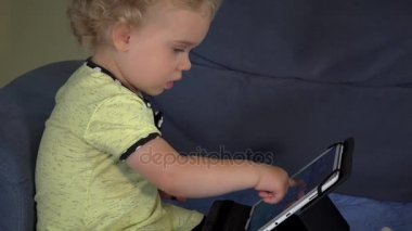 Tablet bilgisayar ekranı kanepede oturan dokunmadan meraklı sarışın çocuk