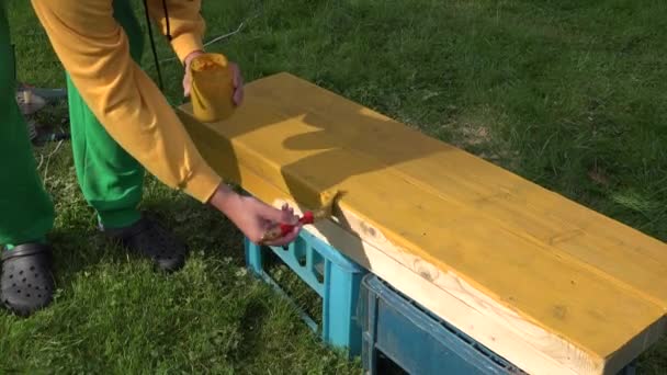 Mani maschili di pittore che tengono pennello e vaso con vernice pittura superficie in legno di colore giallo. 4K — Video Stock