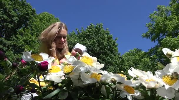 Baby girl with mommy first time smell peony flower blooms 4K — Stock Video