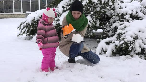 Speelse moeder met dochter opgewekt meisje sneeuw kasteel bouwen en vernietigen — Stockvideo
