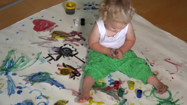 Yürümeye başlayan çocuk kirli pastada renkli boya koymak.. — Stok video
