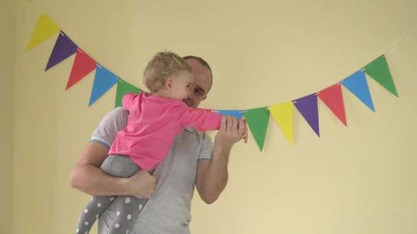 Молодий щасливий батько тримає доньку на руках і вони танцюють вдома — стокове відео