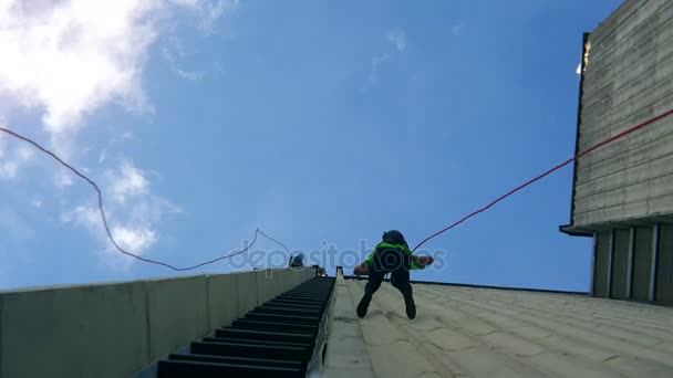 Furchtlose Menschen steigen mit Sicherungsseil an Wolkenkratzer hoher Hauswand ab. — Stockvideo