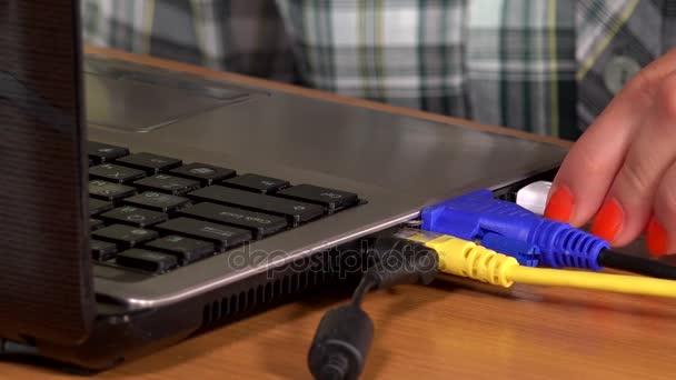 Vrouwelijke hand loskoppelen lan, USB- en VGA-kabels van de laptop op tafel — Stockvideo