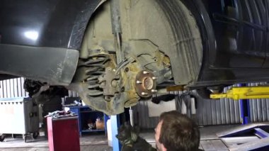 Fren sisteminin paslı cıvataları sökerek büyük somun anahtarı kullanan adam. El.