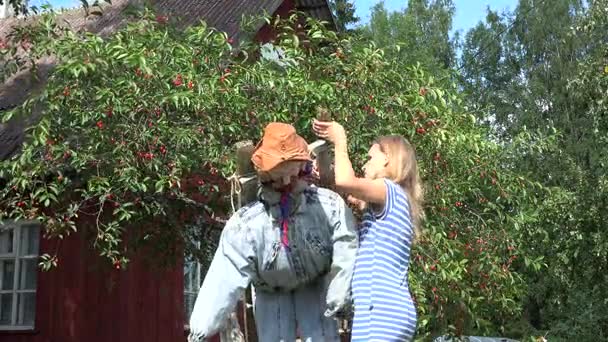 Villager girl stand scarecrow on cherry tree to protect berries. 4K — Stock Video