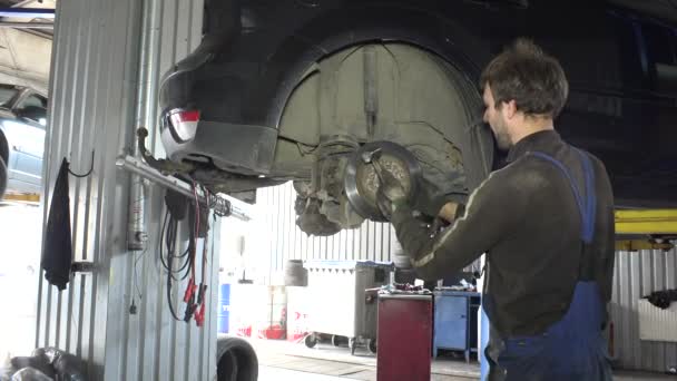 Mechaniker schlug mit Hammer auf Bremsscheibe von rostigem Auto ein. — Stockvideo