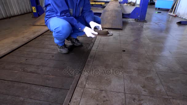 Mechanic hand showing worn rusty brake disk at garage. — Stock Video