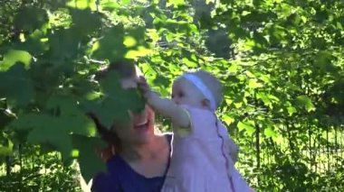 Bebek kızı ile neşeli anne Lale ağacı dalları arasında iyi eğlenceler. 4k