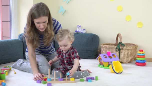 Batole dívka s její matkou hrát vytáhnout dřevěné barevné kostky na sloupech doma. — Stock video