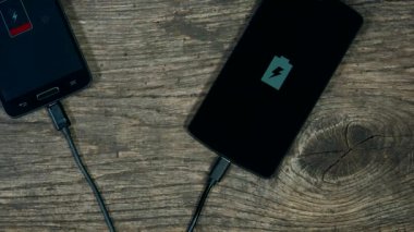 akıllı telefonlar Grunge ahşap arka plan üzerinde şarj. Durumunu ekranda.