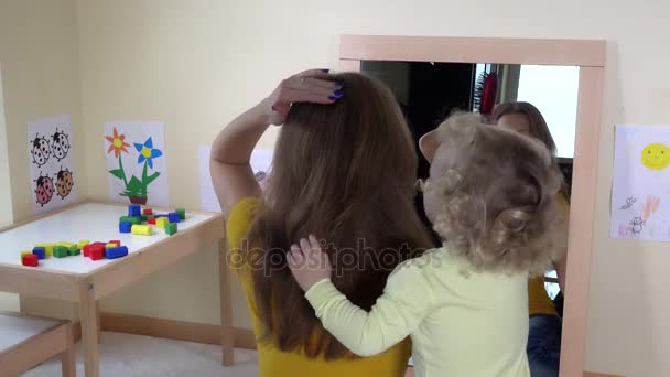 Blond tout-petit fille fille peigner ses cheveux de mère devant le miroir — Video