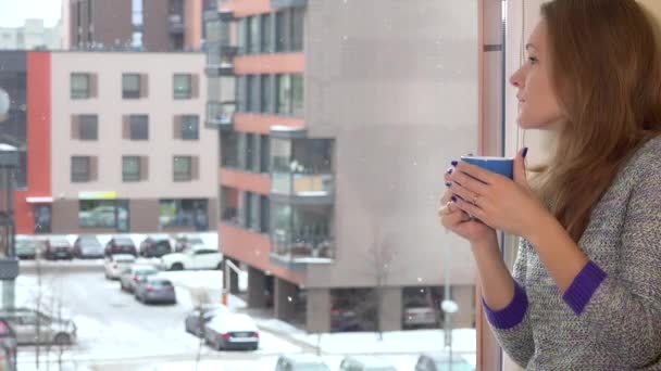 Ernsthafte Frau blickt mit Tasse Tee Kaffee und Traum durch das flache Hausfenster — Stockvideo