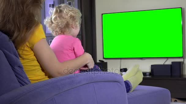 Young mother with her daughter girl relax on sofa and watch tv. Green screen — Stock Video