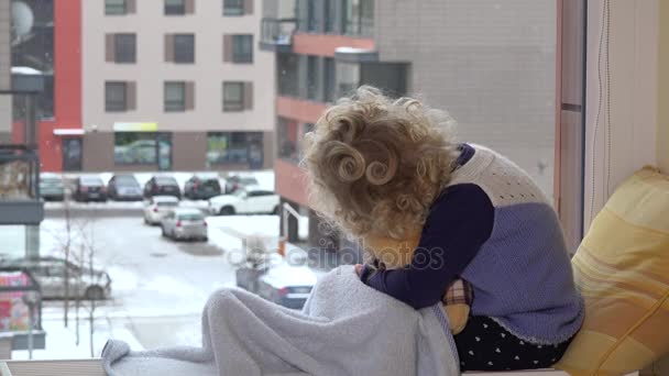 kid with best friend teddy bear caress and kiss looking at snow fall