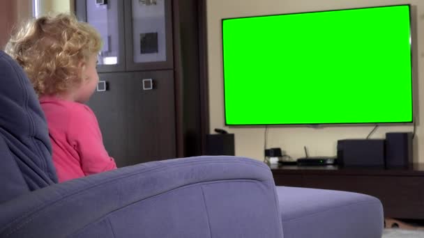 Söt liten flicka sitter på soffan och tittar på tv hemma. Gröna Färgtransparens — Stockvideo