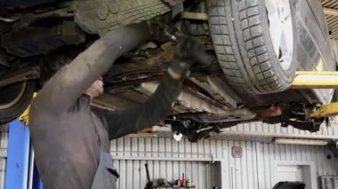 Erkek araba tamircisi otomobil garajında çalışan somun anahtarı ile