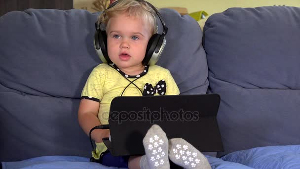 Roztomilé batole dívka se sluchátky pomocí tabletu a poslechu hudby — Stock video