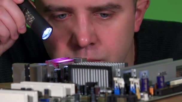 Ingeniero hombre mirando la placa base de la computadora con la luz del flash — Vídeos de Stock
