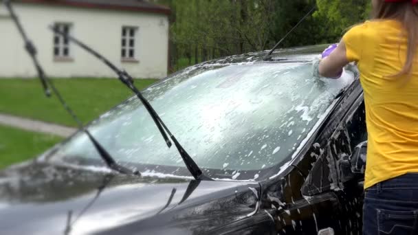 Žena čištění špínu z auta s houbou a automobilové šampon. — Stock video