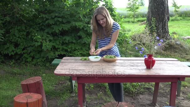 Eine glückliche Vegetarierin reicht frische grüne Erbsen auf einen roten Holztisch. 4k — Stockvideo