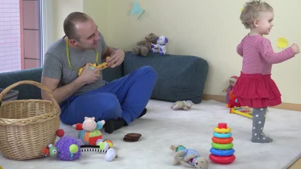 Ο πατέρας παιχνίδι με παιχνίδι κιθάρα και χαριτωμένο μωρό κόρη της χορό. 4k — Αρχείο Βίντεο