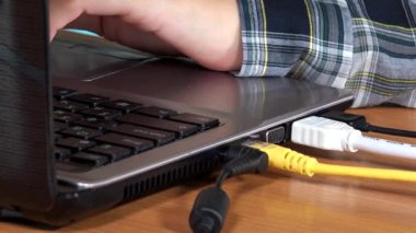 Laptop klavye ve touchpad üzerinde yazmadan eller. Kabloların bağlı.