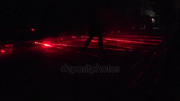 Les gens marchent au laser formé des lignes rouges dans le parc spectacle de lumière nocturne. 4K — Video