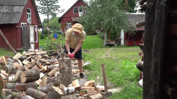 El joven campesino prepara leña orgánica sobre el fondo de las casas rurales. 4K — Vídeo de stock