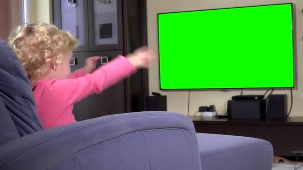 Schattig kind kijken naar tv en dansen verplaatsen handen. Groene chroma key scherm — Stockvideo