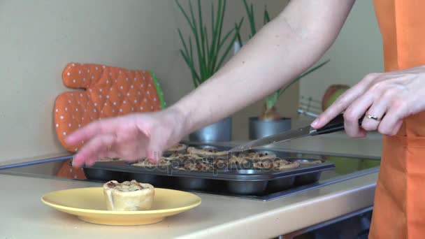 As mãos de mulher tiram bolos de xícara de carne cozidos no forno da folha de biscoito e instalam no prato — Vídeo de Stock