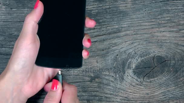 Vrouwelijke hand hechten slimme telefoons aan draden van de lader — Stockvideo