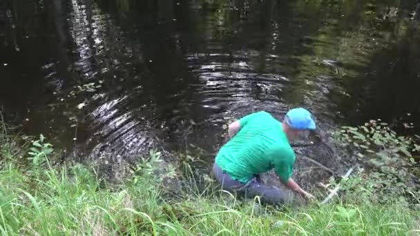 Pêcheur pêcheur homme nettoyer l'eau du lac privé des plantes et des déchets. 4K — Video