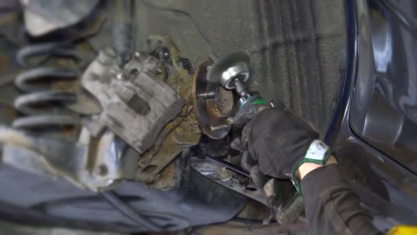 Μηχανικός εργαζόμενος άνθρωπος άλεσμα σκουριασμένα μπουλόνια με ηλεκτρικό μύλο εργαλείο κοντά σε ανυψωμένη αυτοκίνητο — Αρχείο Βίντεο