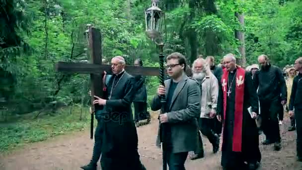 Sacerdote e uomo dalla testa grigia portano la croce come Gesù Cristo. Processione religiosa — Video Stock