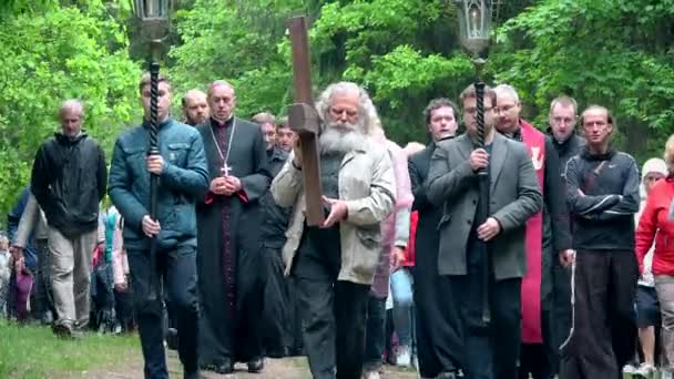 Gris anciano llevando cruz como Jesucristo delante de la procesión religiosa — Vídeo de stock
