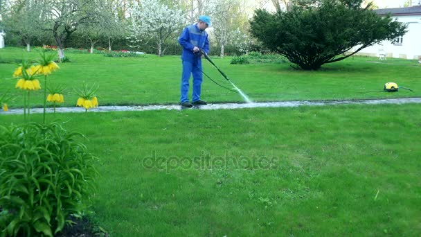 Tuinman man wassen voetpad met hoge druk waterstraal. — Stockvideo